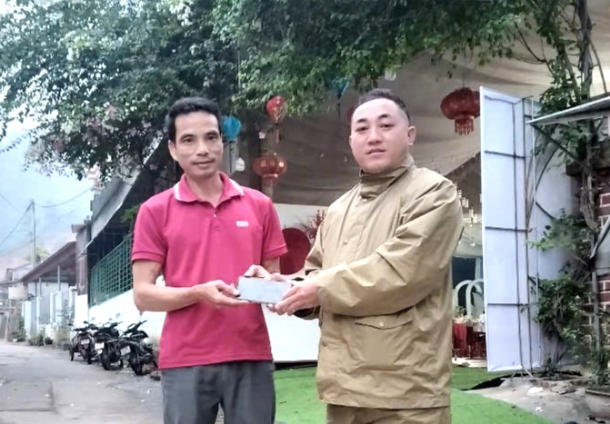 Thượng uý Lầu Văn Thành (bên phải) trao trả tài sản cho anh Hoàng Văn Lân.